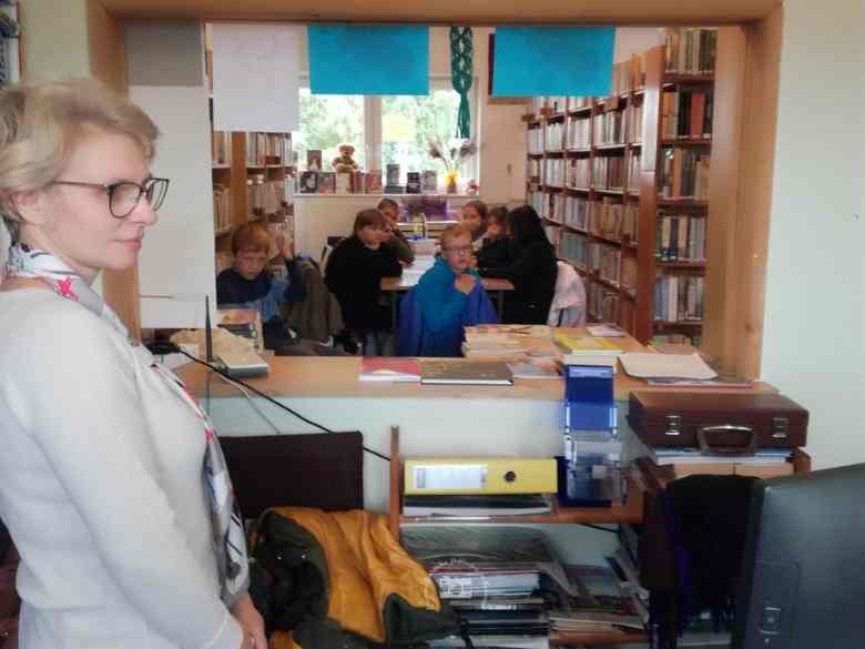 Biblioteka wewnątrz, Nauczycielka, dzieci, ekran, komputer, krzesła, dzieci, regały, śiciana