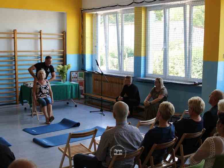 Sala gimnastyczna, stół, obrus, ławki, krzesła, Mariusz, widownia, maty, stojak na mikrofon, okna