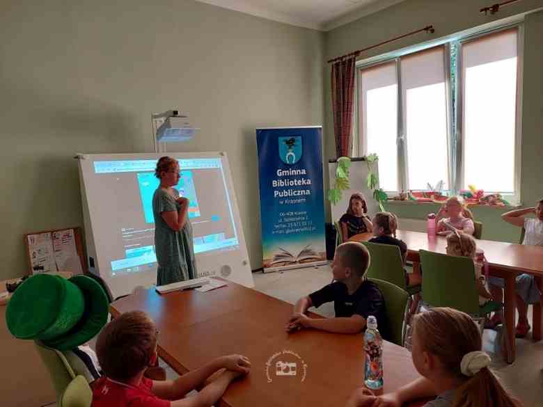 Sala konferencyjna biblioteki, magiczna ściana, dzieci, stoły, baner biblioteczny, ściana