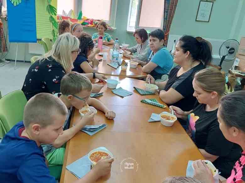 Sala konferencyjna biblioteki, turystyczna kuchenka elektryczna, garki, stół, dzieci,