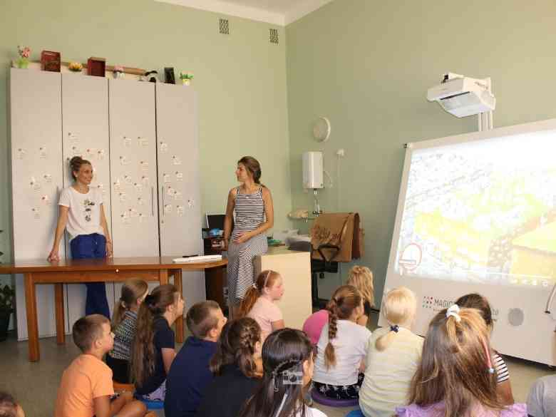 Katarzyna Magnuszewska, Dorota Kryściak i dzieci na sali konferęcyjnej oglądają materiał video