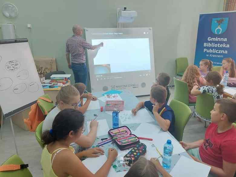 Sala konferencyjna, magiczna ściana, dzieci, stoły, krzesła, baner, kartki papieru, kredki